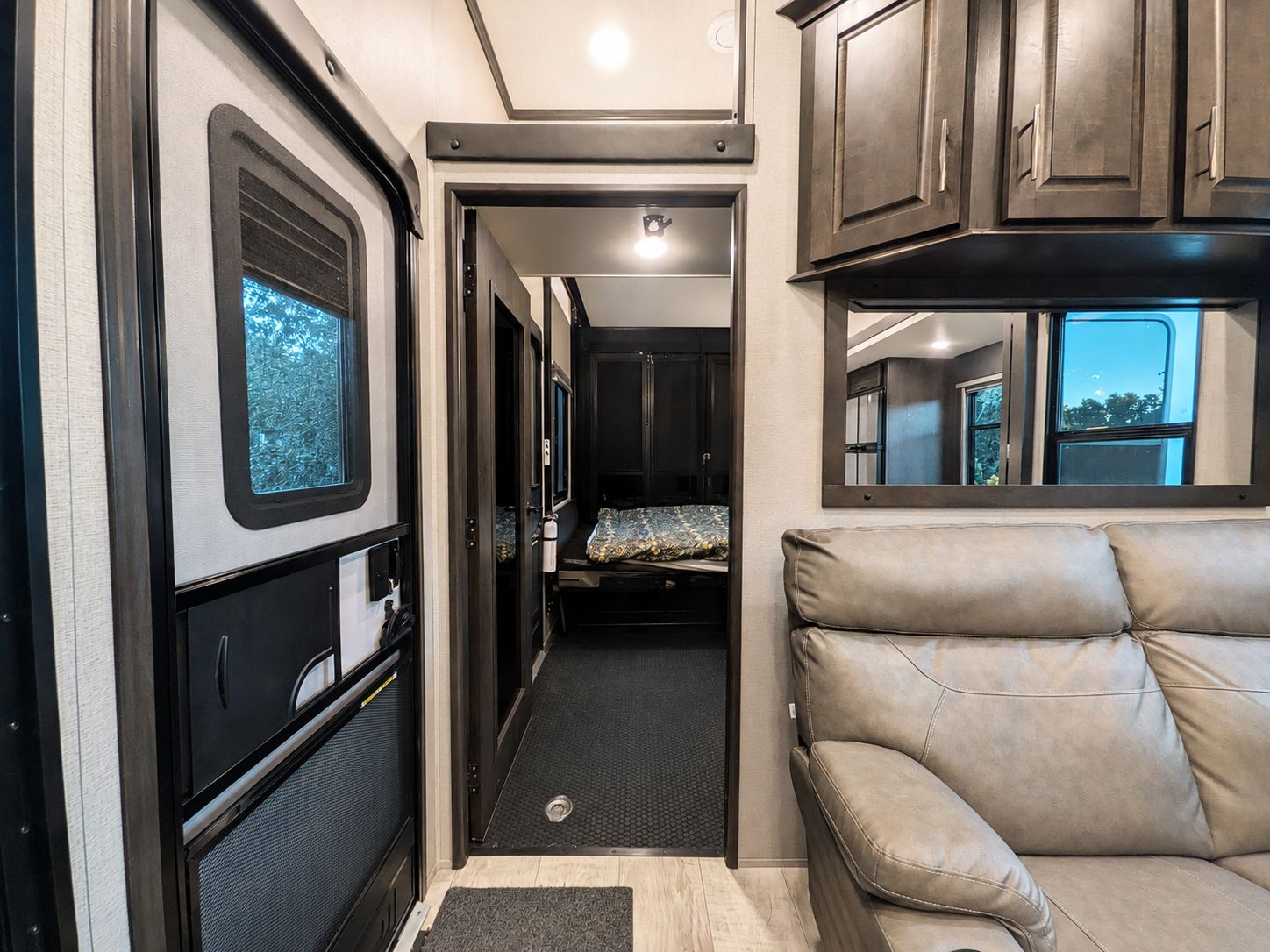 A compact RV interior with a kitchenette, a sleeping area, and a seating space.