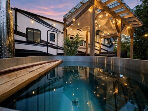 Ein Schwimmbecken mit Holzterrasse, umgeben von einer überdachten Außenbereich mit Lichterketten.