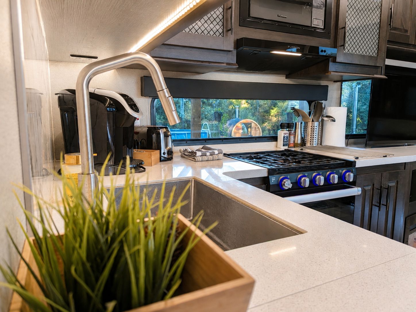 Een moderne keuken met een ingebouwde kookplaat, een gootsteen en een raam met uitzicht op groen.