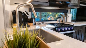 Een moderne keuken met een ingebouwde kookplaat, een gootsteen en een raam met uitzicht op groen.