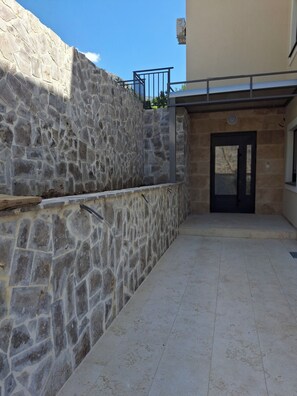A stone wall with a metal railing and a door leading to a building. - Cozy 1-bedroom apartment in fantastic Kotor with AC (Kotor)