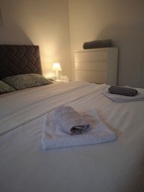 A neatly made bed with a folded towel and a rolled towel on a white mattress in a hotel room. - Cozy 1-bedroom apartment in fantastic Kotor with AC (Kotor)