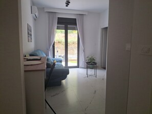 A modern living room with a sofa, a small table, and a potted plant. - Cozy 1-bedroom apartment in fantastic Kotor with AC (Kotor)