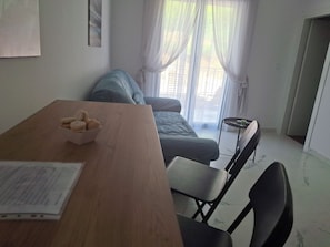 A room with a wooden table, a chair, a sofa, and a window with curtains. - Cozy 1-bedroom apartment in fantastic Kotor with AC (Kotor)