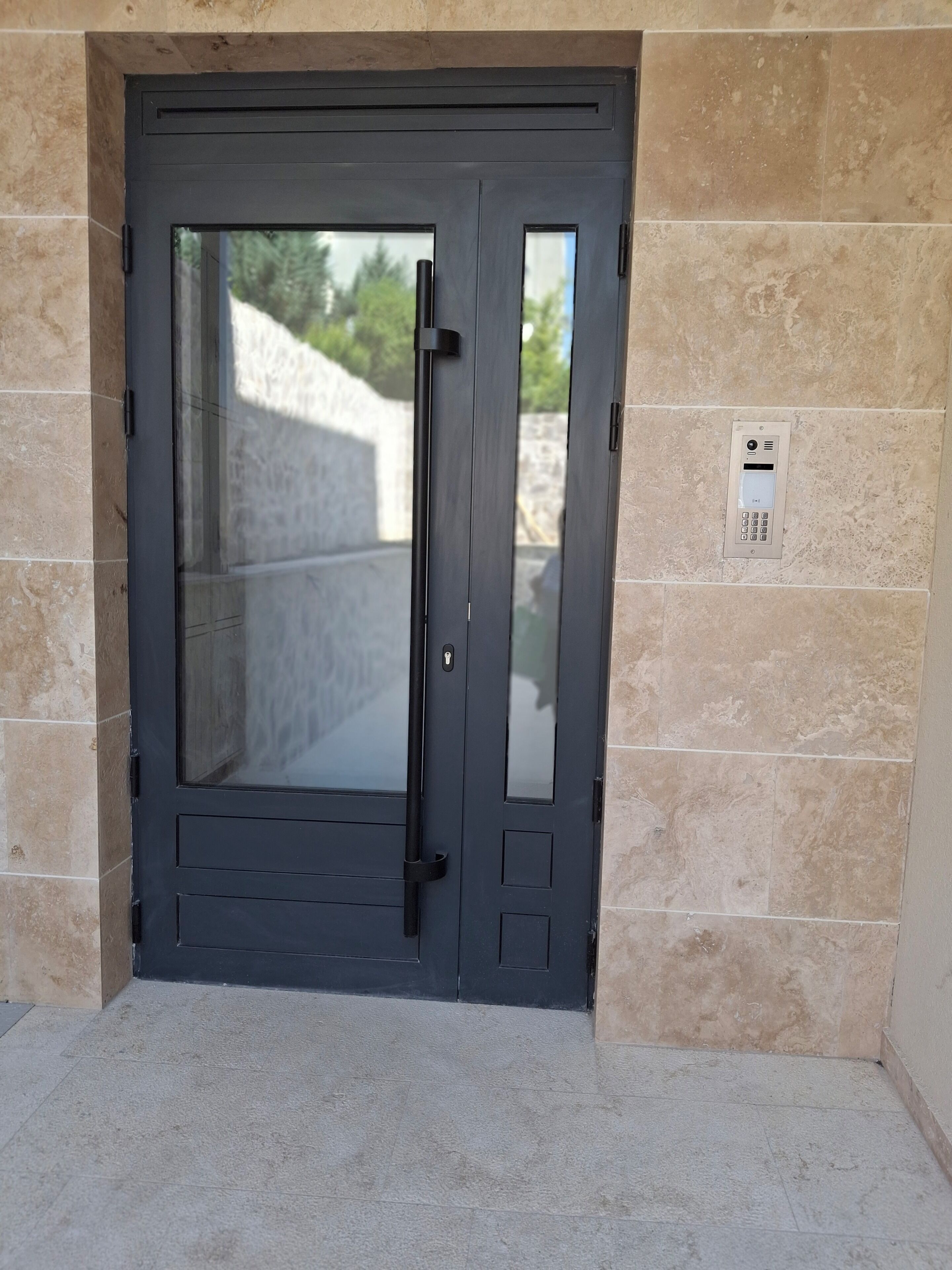 A modern door with a keypad lock, set in a stone wall.