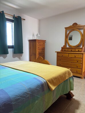 A bedroom with a bed, a wooden dresser, a mirror, and a window with curtains. - SOUTHERN STAR (Valle La Lajita)