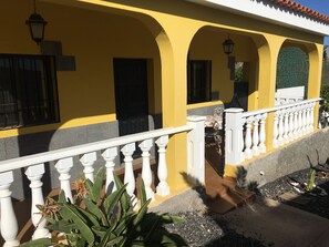 Un bâtiment jaune avec des balustrades blanches et un patio couvert.