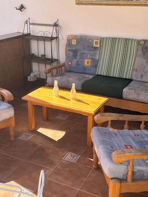 Un coin salon confortable avec un canapé, deux fauteuils et une table en bois sur laquelle sont posées deux bouteilles.