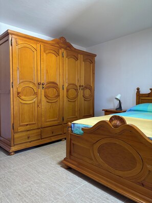 Ein Schlafzimmer mit einem Holzkoffer, einem Bett mit Kopfteil und einem Nachttisch mit Lampe.