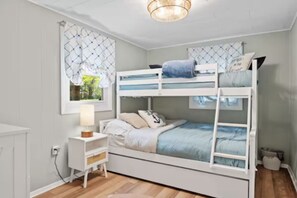 Ein Schlafraum mit Etagenbetten, Fenster, Nachttisch und Lampe.