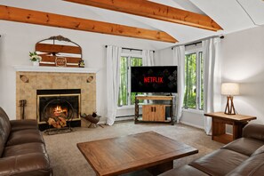 Ein Wohnzimmer mit Kamin, Fernseher und einer Couch.