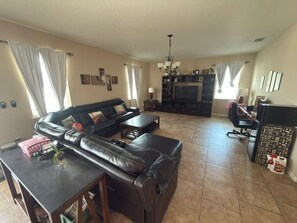 A living room with a sofa, coffee table, TV, and a desk with a computer. - CLOSE TO DISNEY 45 m. Cozy 3bed 3bath house in Apopka w fitness room-pool! (Apopka)