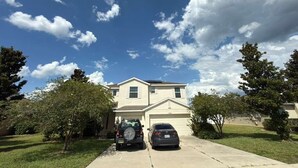 A two-story house with a garage, parked cars, and a lawn. - CLOSE TO DISNEY Cozy 3 bed/3 bed house in tranquil Apopka w fitness room/ pool (Apopka)