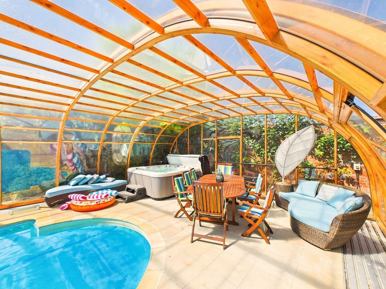 A covered outdoor area with a pool, seating, and hot tubs.