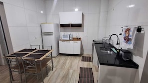 Une cuisine compacte comprenant une table à manger, des placards, un four à micro-ondes et un évier.