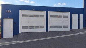A building with numbered garage doors labeled A through E, and a number 155 on the wall. - Vrbo Property (Araçariguama)