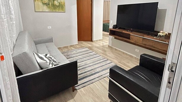 A living room with a sofa, a television, and a painting on the wall. - Vrbo Property (Araçariguama)