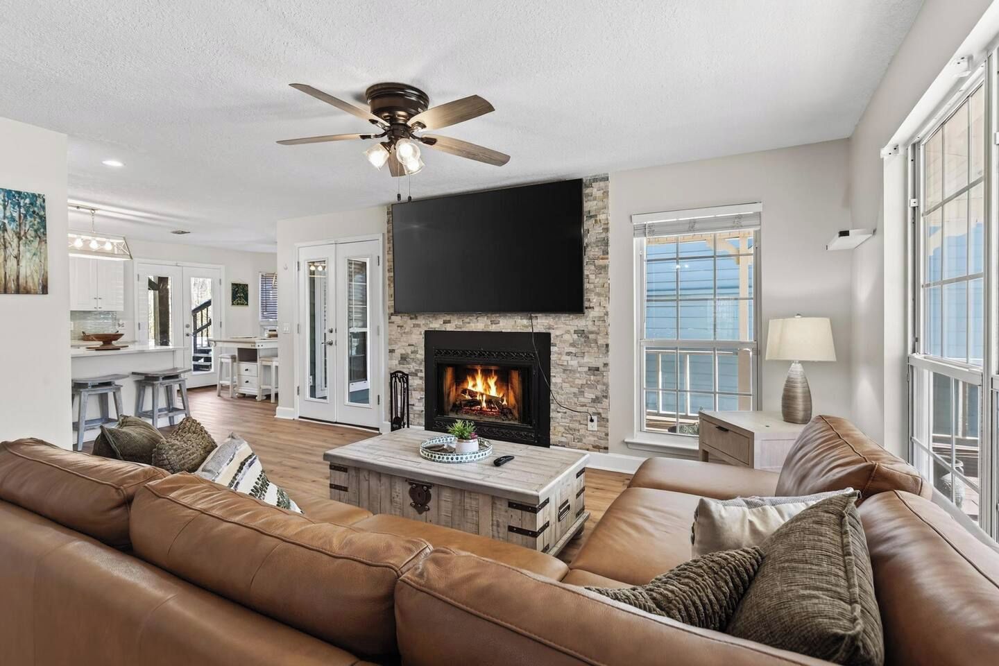 A modern living room with a fireplace, leather sofa, and a dining area in the background.