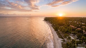 A coastal landscape with a beach, palm trees, and a sunrise or sunset. - Sol e Mar Carneiros Duplex | 2 Suites for 6 People | 300 m from the beach | (Tamandaré)