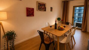 A dining area with a wooden table, chairs, a wine bottle, and a fruit bowl. - Lisbon Green Center (Lisboa)