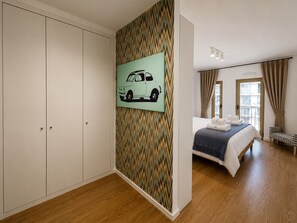 A bedroom with a bed, a wardrobe, a patterned wall, and a window with curtains. - Lisbon Green Center (Lisboa)
