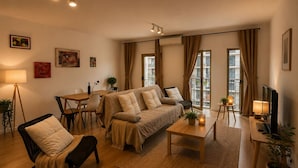A modern living room with a sofa, coffee table, and dining area. - Lisbon Green Center (Lisboa)