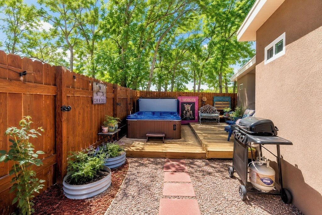 En trädgård med en bubbelpool, en grill och en täckt uteplats.