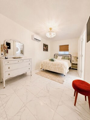 A bedroom with a bed, dresser, mirror, and a chandelier. - Cultural NM home close to UNM Plex, NHCC, Downtown, Zoo, Barelas (Albuquerque)