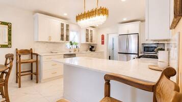 A modern kitchen with white cabinetry, a central island, and a chandelier.