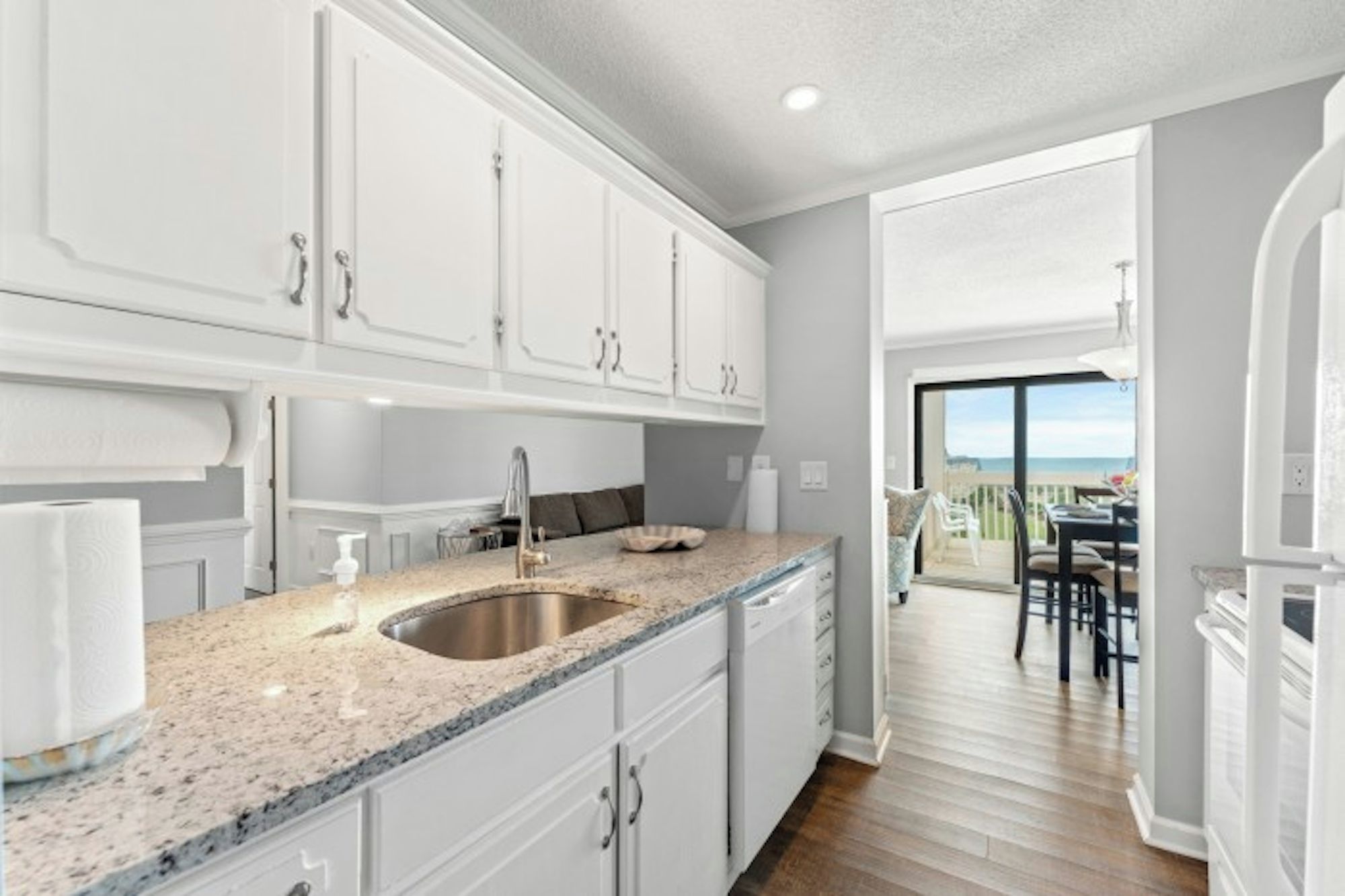 A modern kitchen with white cabinets, a granite countertop, and a stainless steel sink.