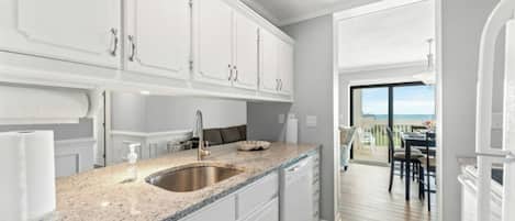 A modern kitchen with white cabinets, a granite countertop, and a stainless steel sink.