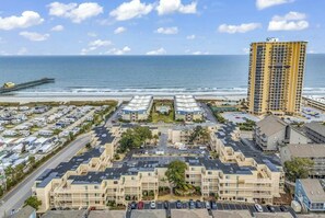 Un complexe hôtelier situé sur la côte, composé de plusieurs bâtiments, doté d’un parking et offrant une vue sur l’océan.