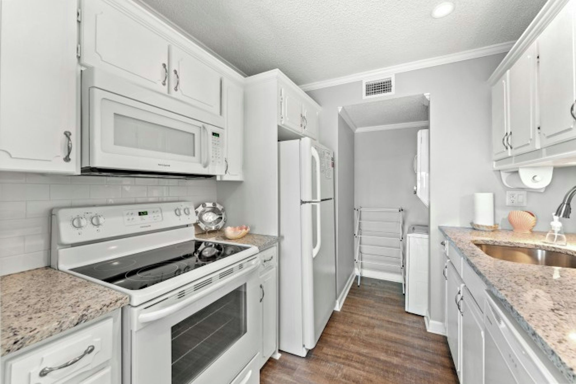 A modern kitchen with white cabinetry, a built-in oven, a microwave, and a refrigerator.