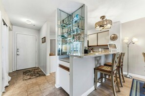 Cuina moderna amb una illa amb vidre, zona de dinar amb cadires i un candelabrum.