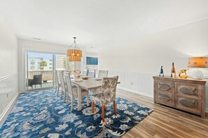 A spacious dining area with a large table, chairs, and a blue patterned rug. - Watergate- 4 Bedroom beach House in Cherry Grove (North Myrtle Beach)