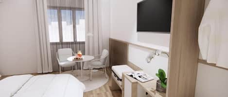 A hotel room with a bed, a desk with a chair, a small table with a chair, a TV mounted on the wall, and a window with curtains.