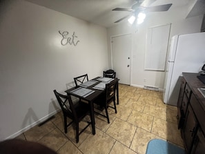 A dining area with a table set for four, a ceiling fan, and a kitchen area with a refrigerator. - Beautiful 2-bedroom apartment near malls and restaurants in Springfield (Springfield)