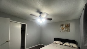 A bedroom with a bed, a ceiling fan, a door, and a wall-mounted light fixture. - Beautiful 2-bedroom apartment near malls and restaurants in Springfield (Springfield)