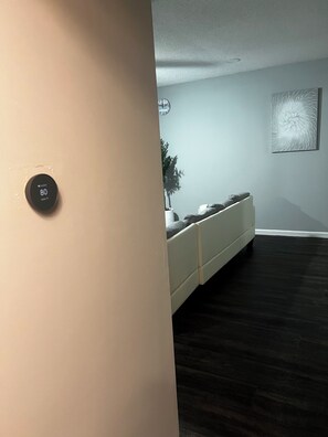 A room with a thermostat, a bed, a wall clock, and a framed artwork. - Beautiful 2-bedroom apartment near malls and restaurants in Springfield (Springfield)