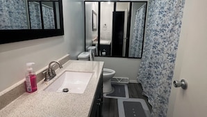 A modern bathroom with a dual sink vanity, a mirror, a toilet, and a shower area. - Beautiful 2-bedroom apartment near malls and restaurants in Springfield (Springfield)