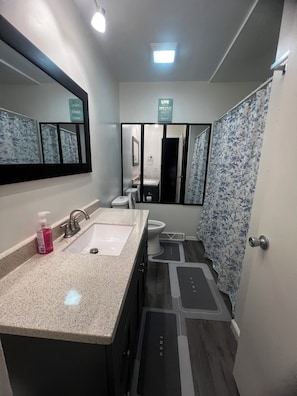Un baño moderno con tocador de doble lavabo, espejo, inodoro y zona de ducha.