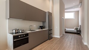A compact kitchen with modern appliances, a built-in oven, and a small dining area with a bench. - Waou Madrid Rio II - Short-Term Rental (Madrid)