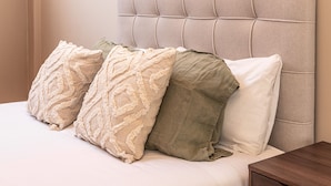 A bed with a headboard, multiple pillows, and a wooden nightstand. - Waou Madrid Rio II - Short-Term Rental (Madrid)