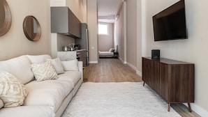 A modern interior with a sofa, a television, a kitchen area, and a hallway. - Waou Madrid Rio II - Short-Term Rental (Madrid)