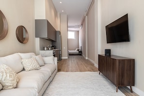 Un interior modern amb un sofà, una televisió, una zona de cuina i un passadís.