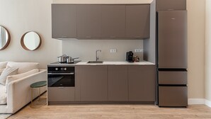 A compact kitchen with a built-in oven, a coffee maker, and a refrigerator. - Waou Madrid Rio II - Short-Term Rental (Madrid)