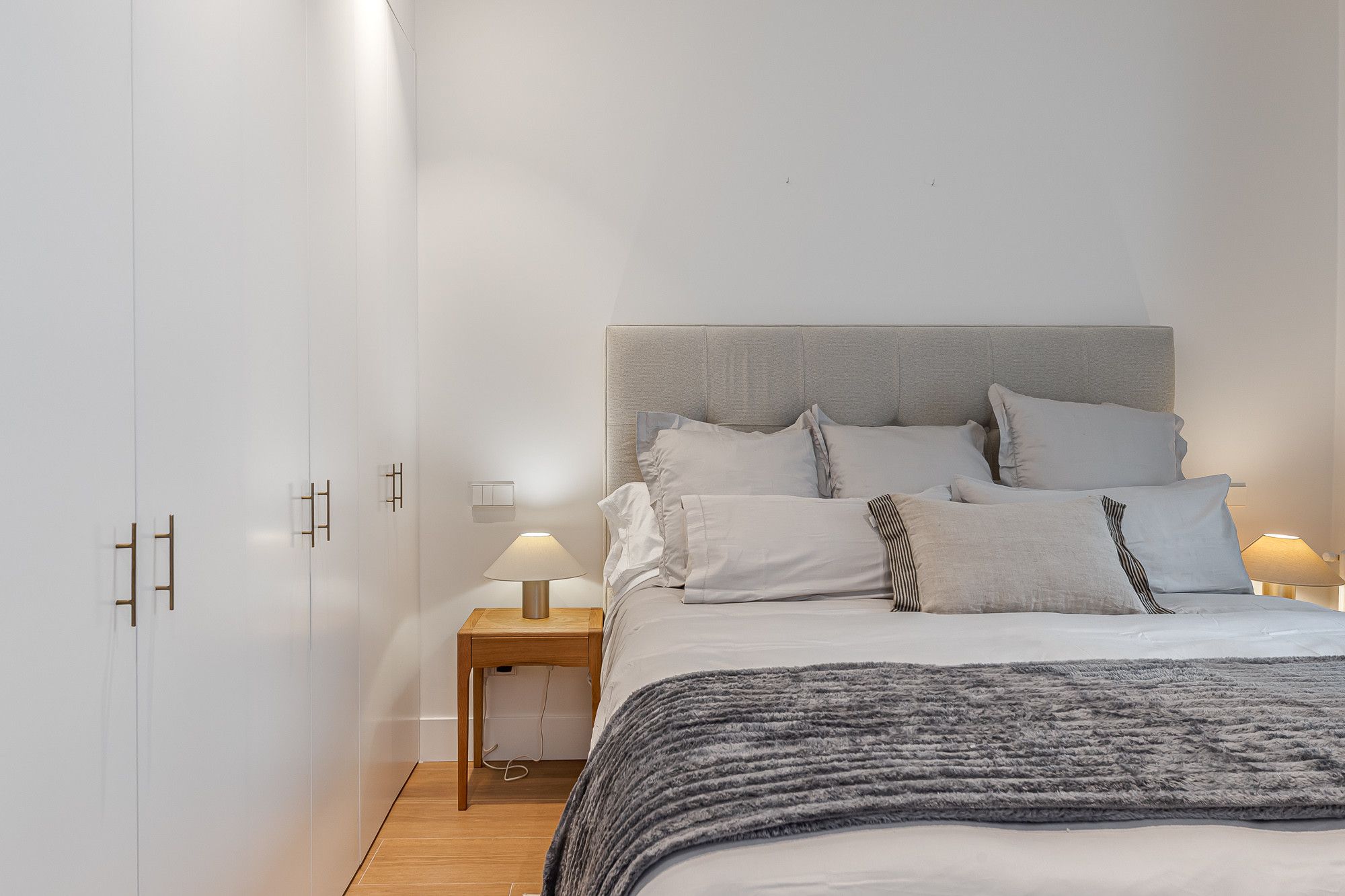 Ein Schlafzimmer mit Bett, Nachttischlampen, einem Nachttisch und einem Kleiderschrank.