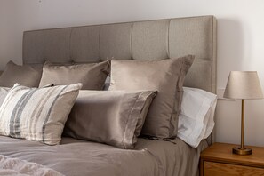 Ein Bett mit vielen Kissen und einer Nachttischlampe.