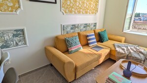 A living room with a sofa, a coffee table, and a window with a view. - Creil 10 min · Paris, CDG 25 min · Asterix 20 min · JW Assembly 2 min (Creil)