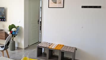A dining area with a table set for two, a bench, and a framed artwork on the wall.
